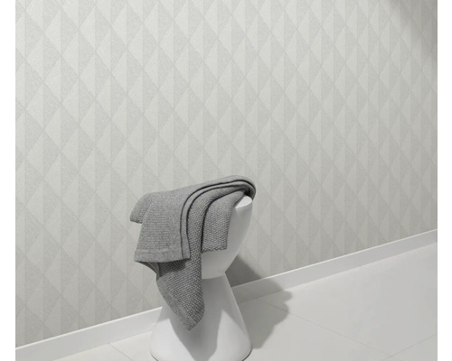 Lichte wand met geometrisch patroon en kruk met deken