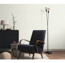 Woonkamer met fauteuil, vloerlamp en dressoir voor een gezellige sfeer.