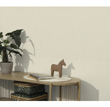 Woonkamer met een gestructureerd behang, gedecoreerd met een plant, een paardenbeeld en boeken op een tafel