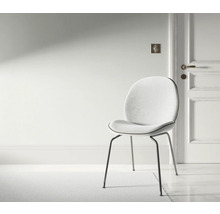 Scene met een stoel met metalen poten en een gestoffeerde zitting in een heldere ruimte.