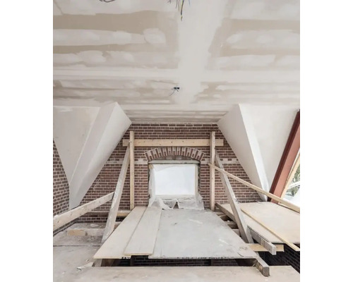 Zolderverbouwing met bakstenen muur en voorbereide raamopening