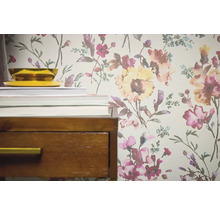 Detailopname van een behang met bloemmotief naast een nachtkastje