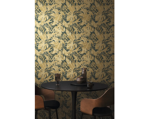 Een kamer met een behang met bladmotief, een eettafel en stoelen.