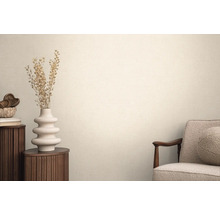 Woonkamer met textielbehang, fauteuil, ronde bijzettafel en decoratie