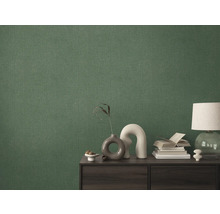 Detailopname van een groen textielbehang op een muur achter een kast.