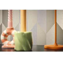 Close-up van een behang met patroon en geometrische vormen op de achtergrond van drie kandelaars.