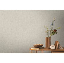 Close-up van een lichte wand met een subtiel patroonbehang dat een rustige en uniforme textuur creëert.