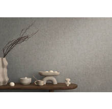 Decoratief stilleven met vaas, schaal en siervoorwerpen op een houten tafel voor een grijze muur.