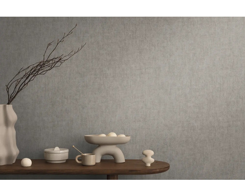 Decoratief stilleven met vaas, schaal en siervoorwerpen op een houten tafel voor een grijze muur.