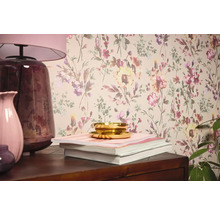 Woonkamerscène met bloemenbehang, tafellamp, vazen, boeken en schaal.