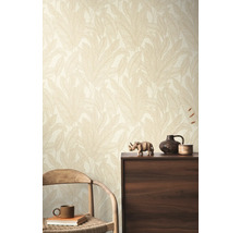 Een kamer met een wandbehang met bladerpatroon, een houten stoel en een donkere houten kast.