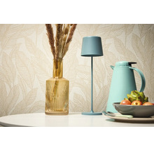 Decoratief stilleven met tafellamp, vaas en thermoskan tegen een achtergrond van een patroonbehang.