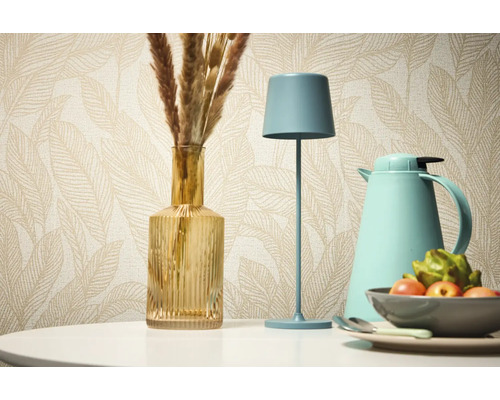 Decoratief stilleven met tafellamp, vaas en thermoskan tegen een achtergrond van een patroonbehang.