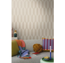 Lichte woonkamer met patroonbehang, grijze bank en decoratieve elementen zoals kussens en dekens