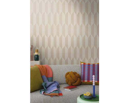 Lichte woonkamer met patroonbehang, grijze bank en decoratieve elementen zoals kussens en dekens