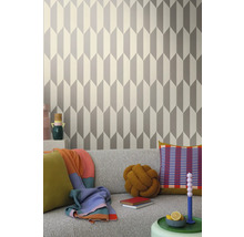 Woonkamer met geometrisch behang in grijs en wit achter een grijze bank