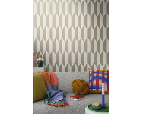 Woonkamer met geometrisch behang in grijs en wit achter een grijze bank