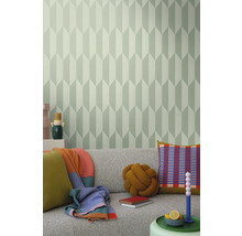 Woonkamer met grijze bank, kussens, dekens en een muur met geometrisch behang