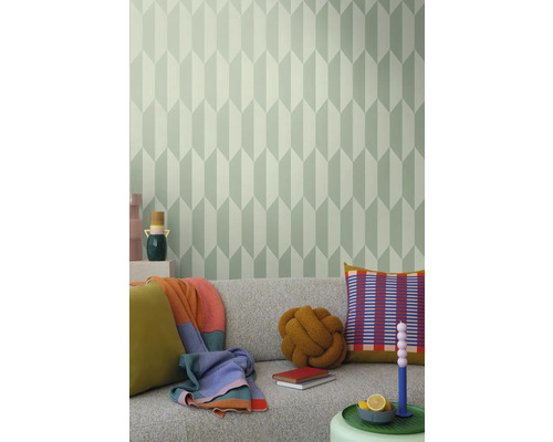 Woonkamer met grijze bank, kussens, dekens en een muur met geometrisch behang