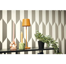 Decoratieve scène met lamp, kaarsen en potplant op een plank voor een geometrisch behang.