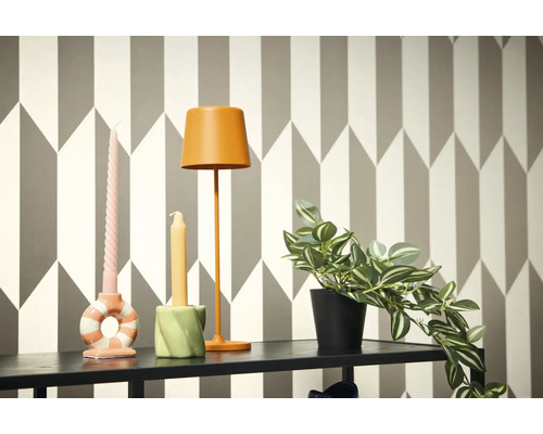 Decoratieve scène met lamp, kaarsen en potplant op een plank voor een geometrisch behang.