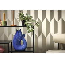 Decoratief interieur met plank, plant en visvaas tegen een geometrisch behang.