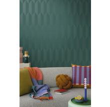 Woonkamer met grijze bank, kussens, dekens en behang met patroon voor een stijlvol interieur.