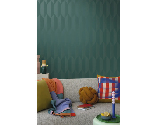 Woonkamer met grijze bank, kussens, dekens en behang met patroon voor een stijlvol interieur.