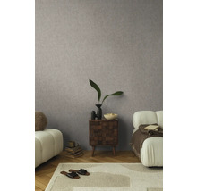 Woonkamer met gedessineerd behang, vloerkleed, bank en bijzettafel.