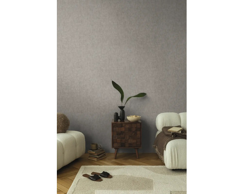 Woonkamer met gedessineerd behang, vloerkleed, bank en bijzettafel.