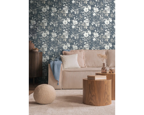 Woonkamer met bloemetjesbehang, bank en houten tafels