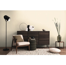 Woonkamerscène met dressoir, fauteuil, staande lamp en decoratieve elementen op een vloerkleed