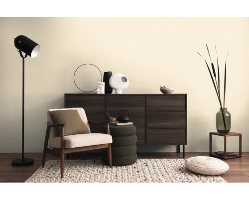 Woonkamerscène met dressoir, fauteuil, staande lamp en decoratieve elementen op een vloerkleed