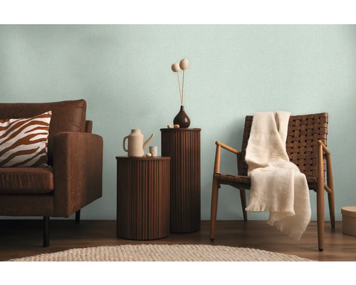 Woonkamer met bank, stoel en bijzettafels in een lichte sfeer