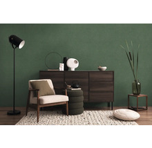 Woonkamer met fauteuil, staande lamp, dressoir en decoraties voor een groene wand