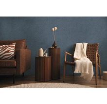 Woonkamer met bank, stoel, bijzettafels en decoratie op blauw gestructureerd behang