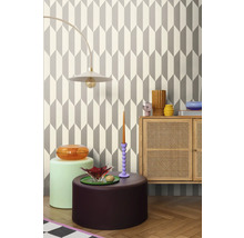 Woonkamer met geometrisch behang, lamp, dressoir en decoratieve objecten voor een stijlvol interieur.