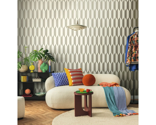 Woonkamer met geometrisch behang, bank, bijzettafel en decoratieve elementen voor een stijlvolle ambiance.