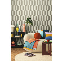 Woonkamer met patroonbehang, bank, bijzettafel en decoraties voor een gezellige sfeer.