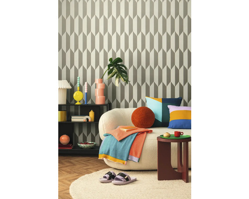 Woonkamer met patroonbehang, bank, bijzettafel en decoraties voor een gezellige sfeer.