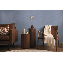 Woonkamer met bank, fauteuil en bijzettafels tegen een blauwe wand