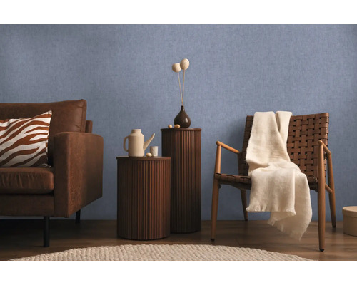 Woonkamer met bank, fauteuil en bijzettafels tegen een blauwe wand