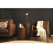 Woonkamer met bank, fauteuil en bijzettafels voor een donkere wand