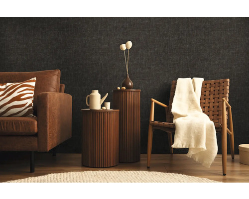 Woonkamer met bank, fauteuil en bijzettafels voor een donkere wand