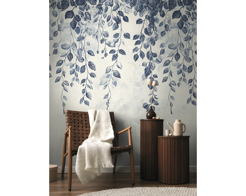 Decoratief behang met bladerpatroon in een stijlvolle woonkamer met fauteuil en bijzettafels.