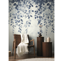 Decoratieve muur met bladerpatroon, fauteuil met deken en bijzettafels in de woonkamer.