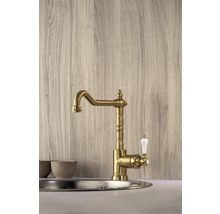 Goudkleurige keukenkraan met witte handgreep gemonteerd in een gootsteen