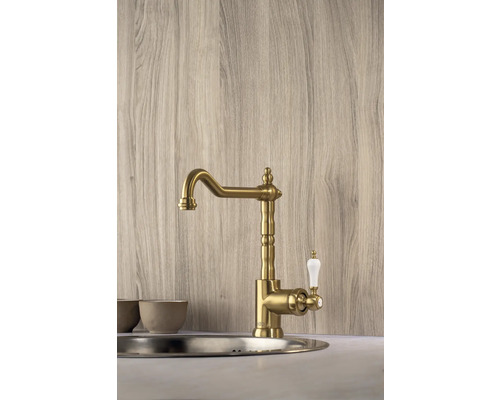 Goudkleurige keukenkraan met witte handgreep gemonteerd in een gootsteen