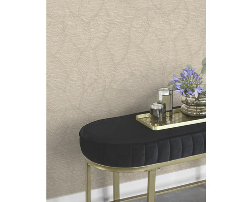 Een wand met patroonbehang achter een bank met bloemen en glazen