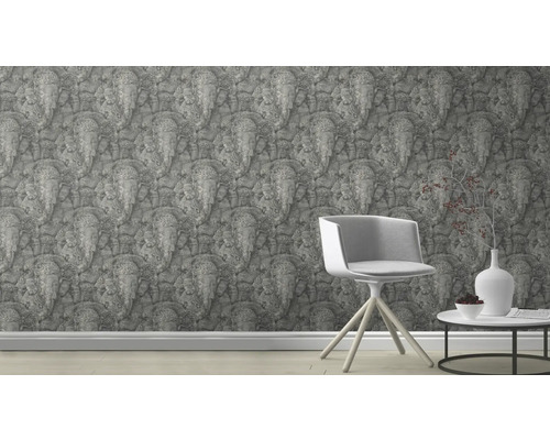 Scene met een behang bedrukt met olifantenreliëfs, een stoel en een tafel met decoratie